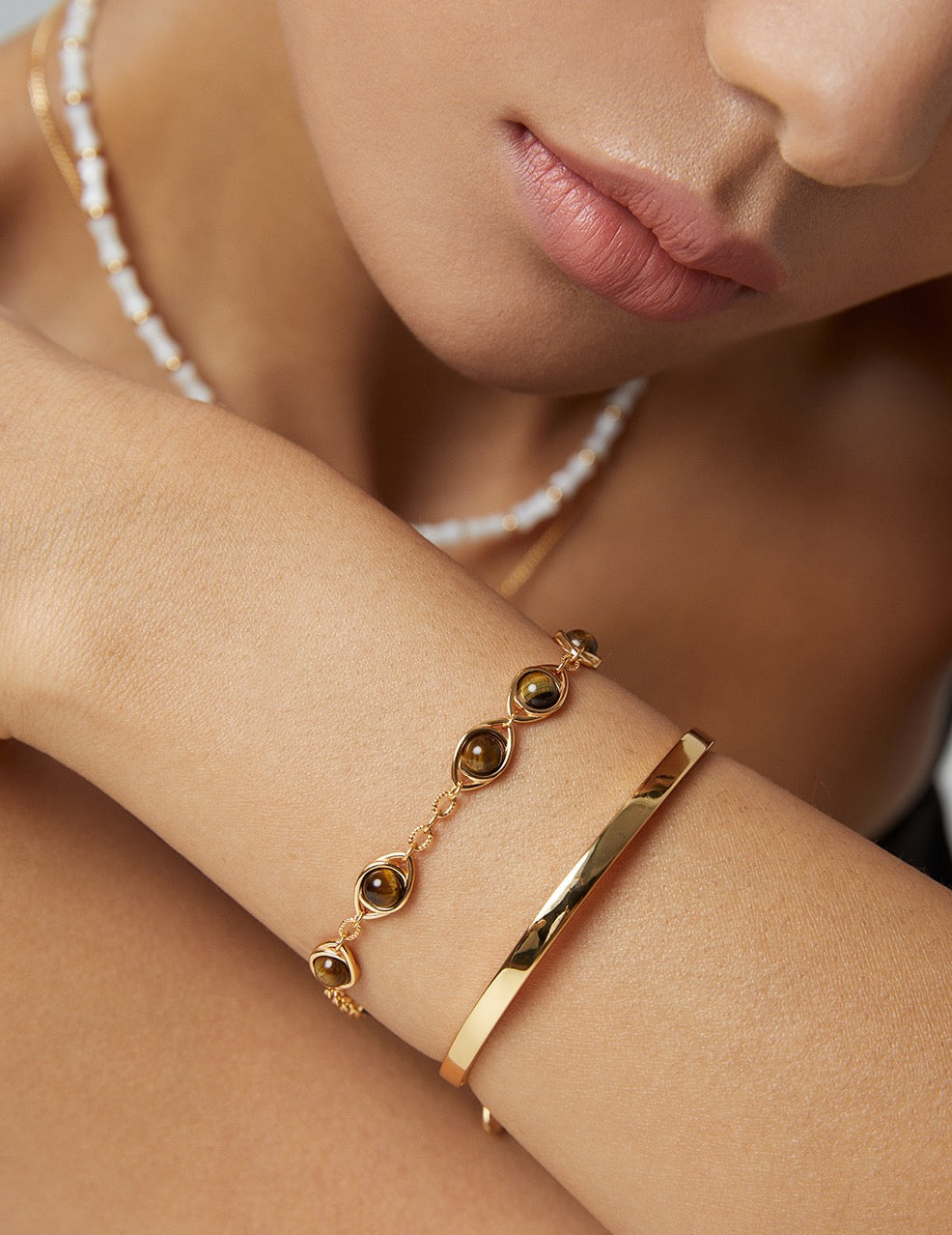 Close-up of a woman's arm wearing a gold bracelet with embedded stones.